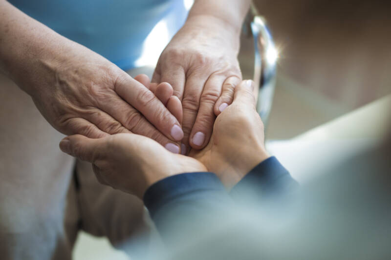 Menschliche Verbindung in der Pflege Eine zuwendungsvolle Pflegekraft eines Nürnberger ambulanten Pflegedienstes hält liebevoll die Hand einer älteren Dame, wodurch Fürsorge und menschliche Wärme symbolisiert werden.